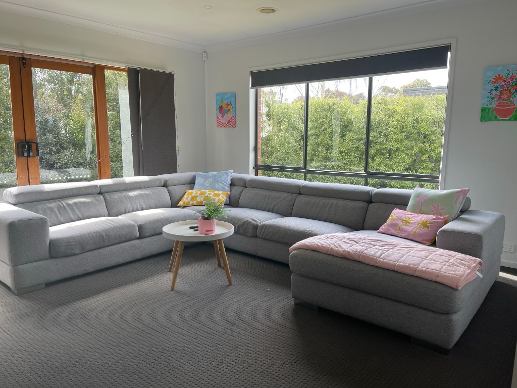 Bright lounge room with L-shaped sofa and views of greenery